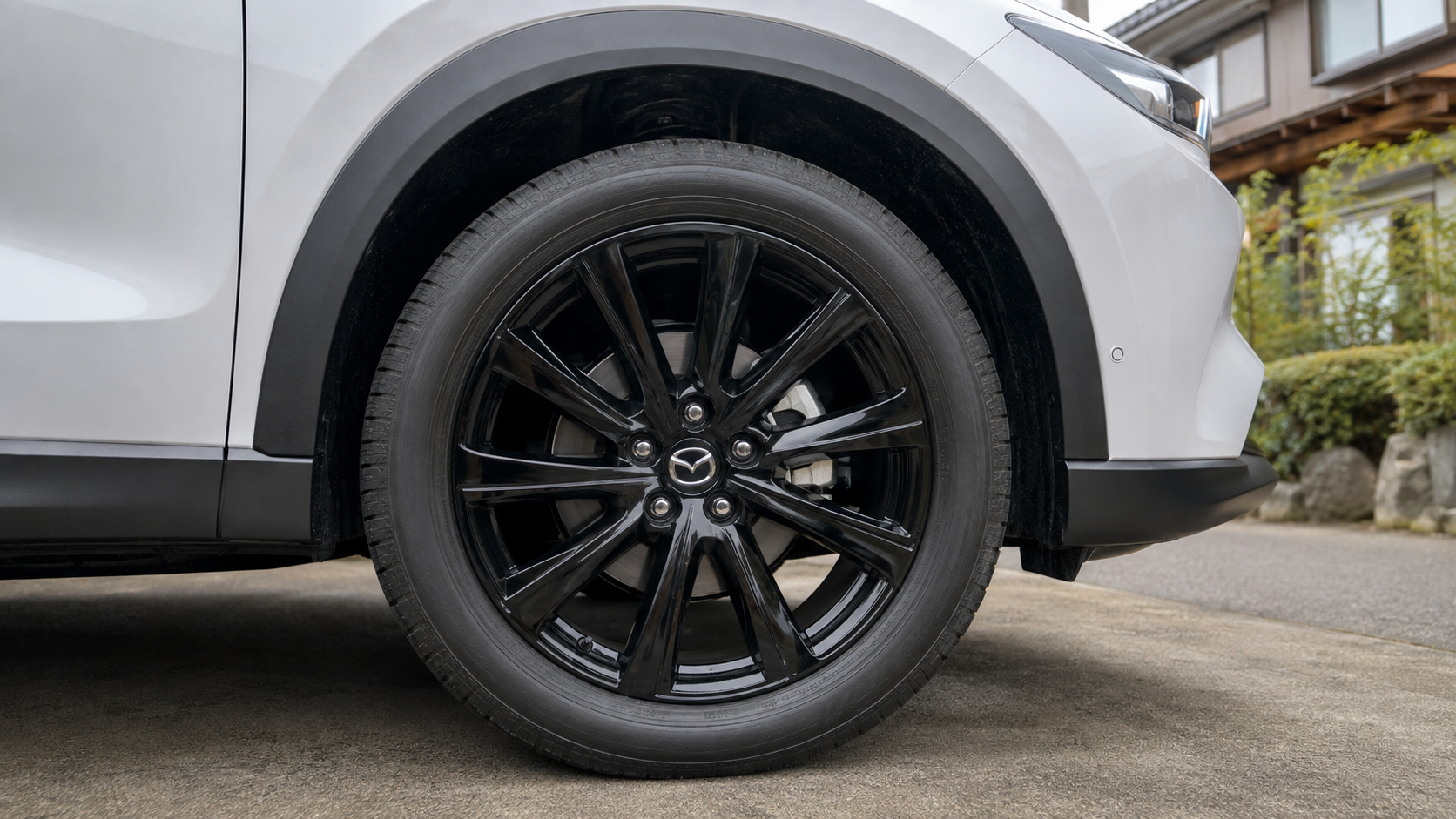 白いマツダCX-5に装着された黒いアルミホイールとタイヤ